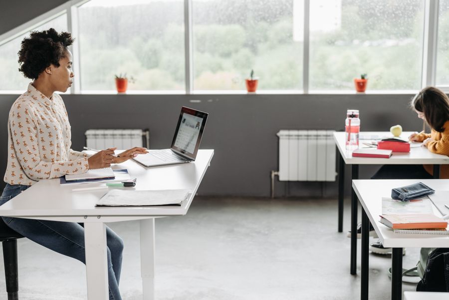 Una docente trabaja con su laptop en una sala de clases